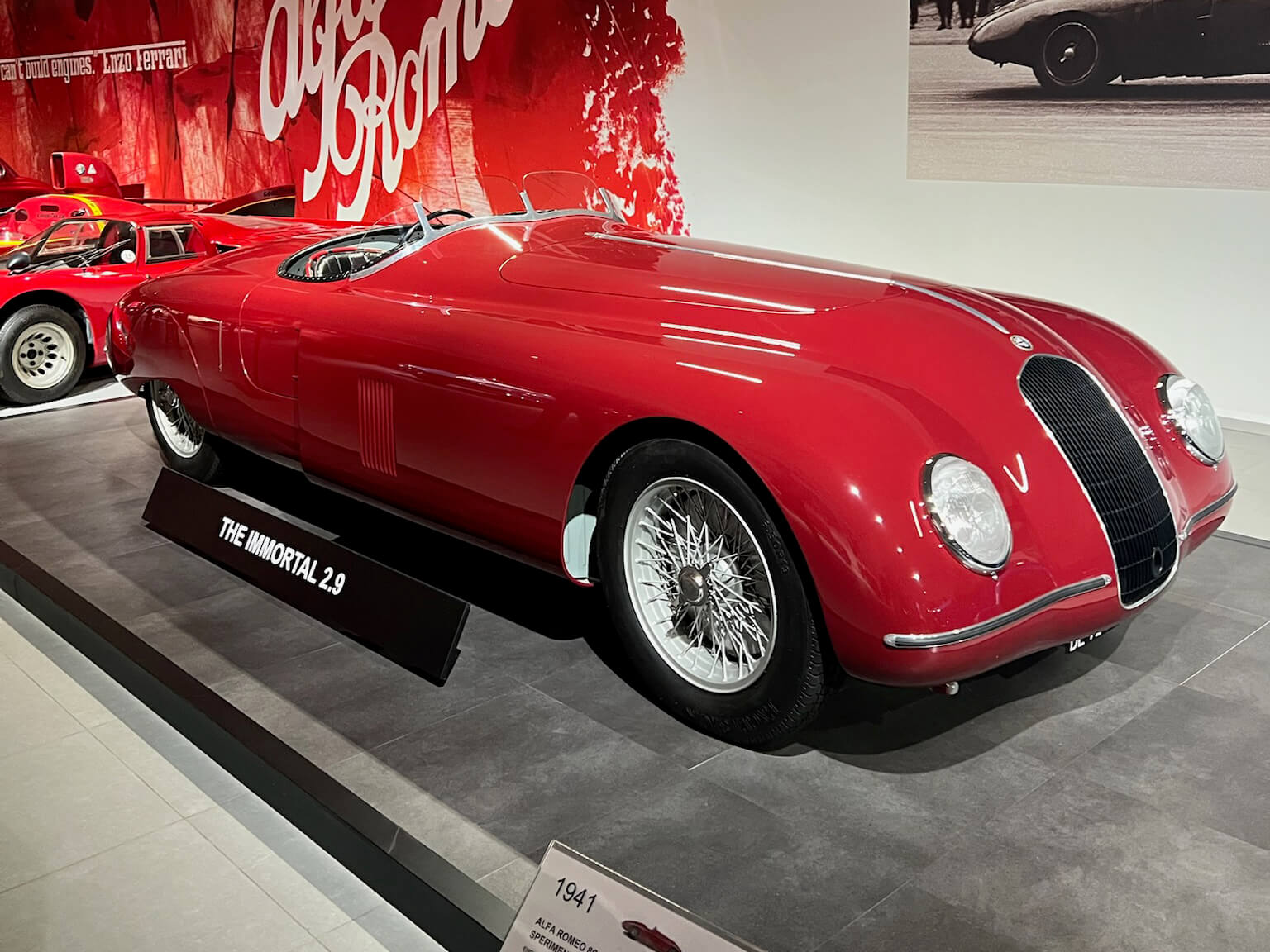 Red Alfa Romeo 8C 2900B Spider Corsa displayed at the Louwman Museum, photographed from a front three-quarter angle with wire wheels and streamlined bodywork